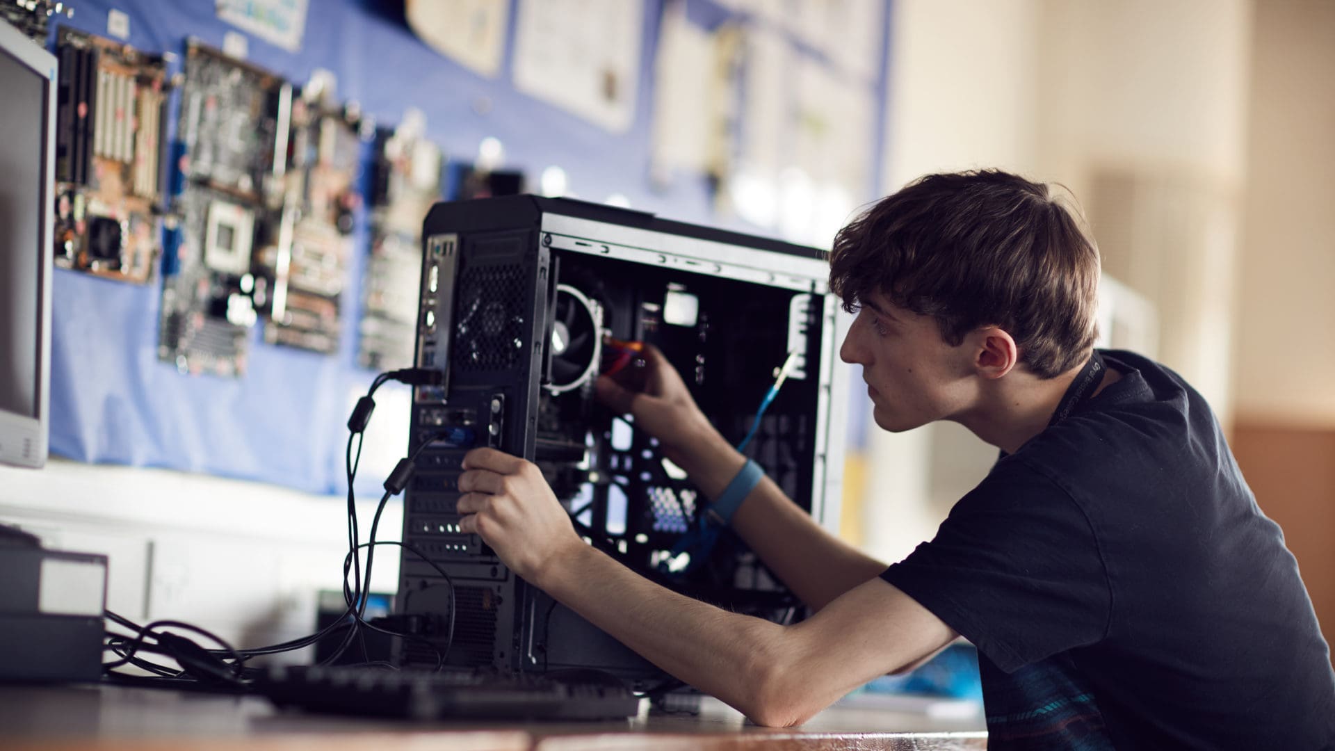 91视频 student focusing on fixing a computer on an IT course